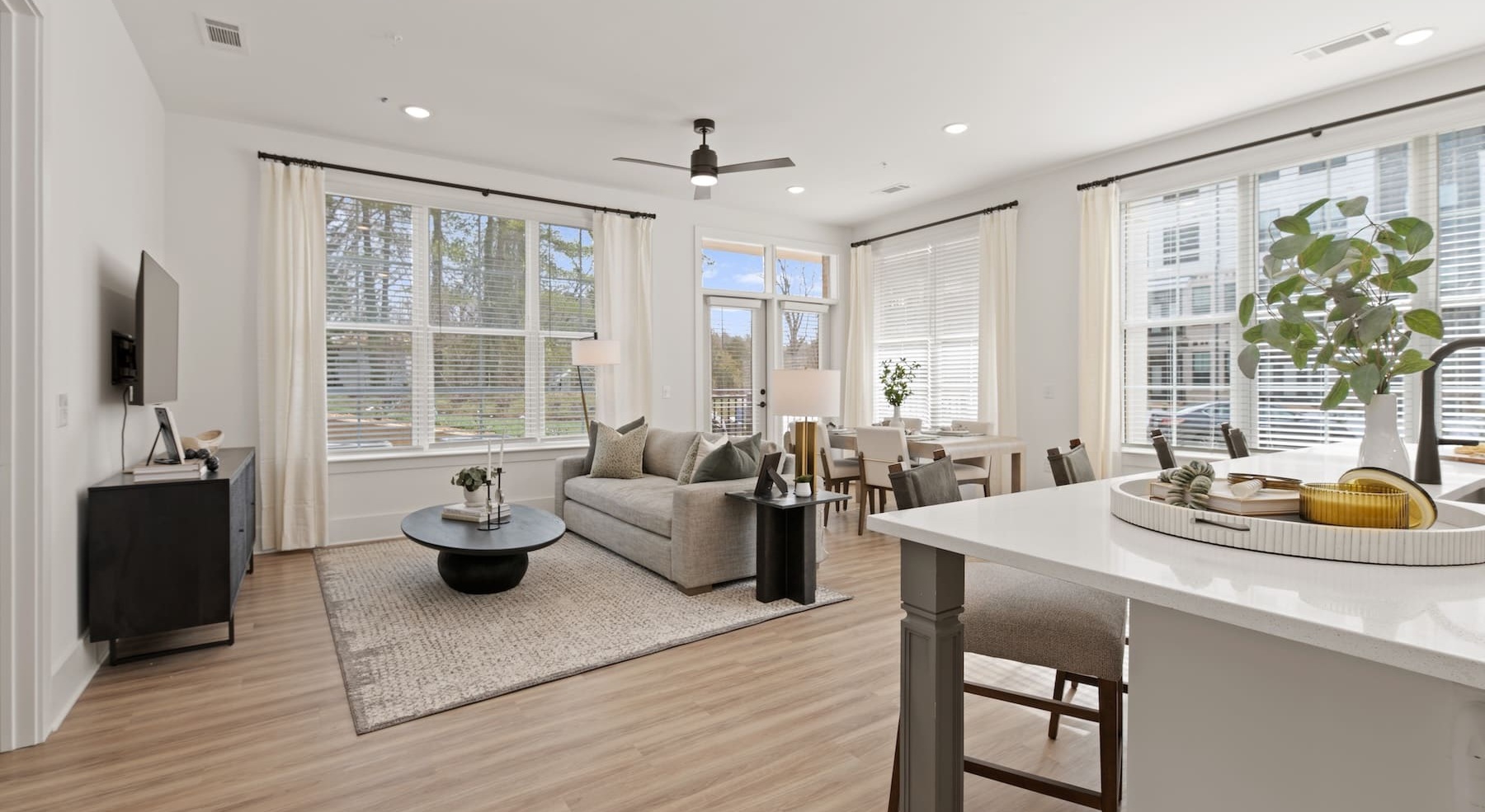 living room, dining and kitchen area with a couch and large windows