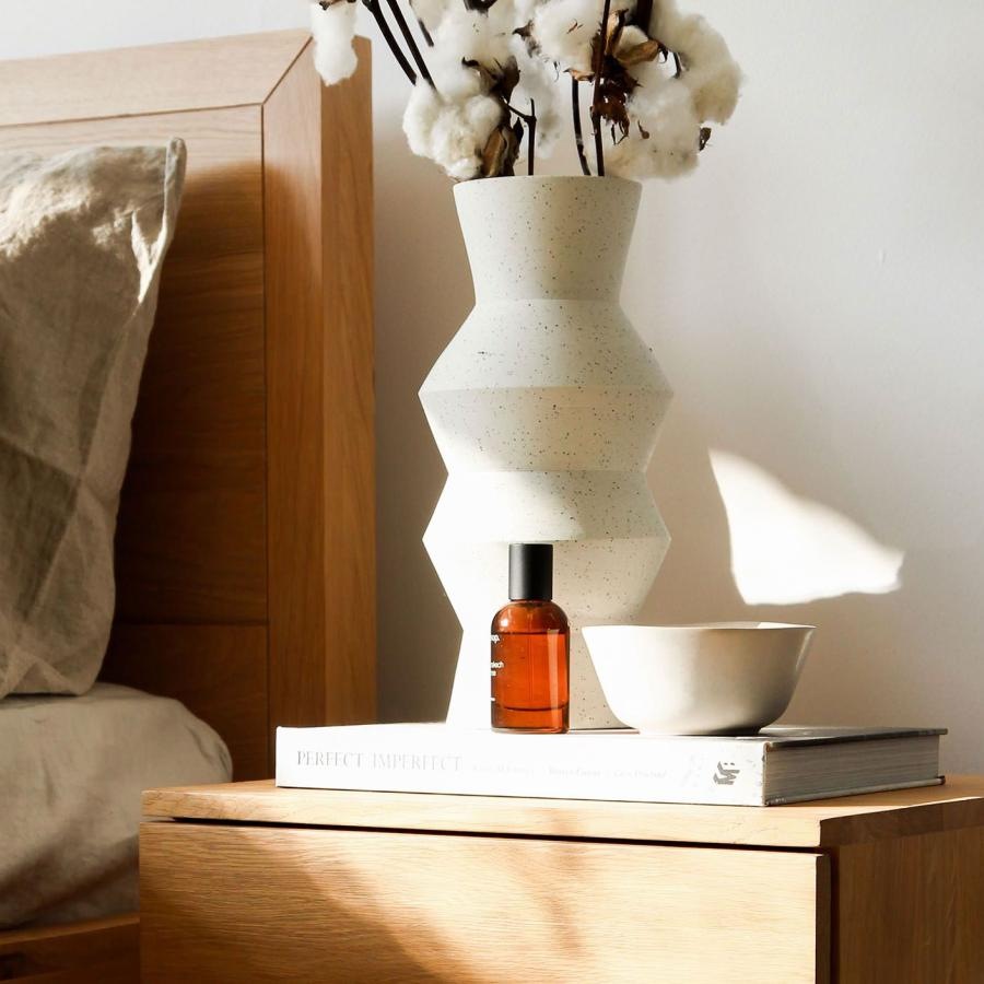 a vase with cotton stems on a bedside table